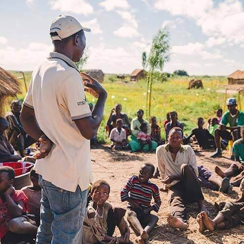 A man speaking to a village in Zambia
